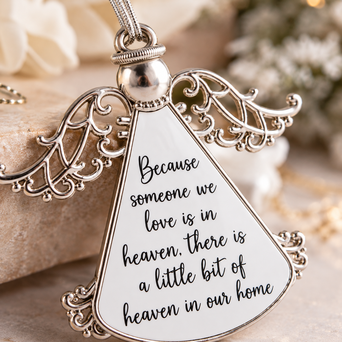 Close-up of silver-tone memorial angel ornament with delicate wings and heartfelt remembrance message
